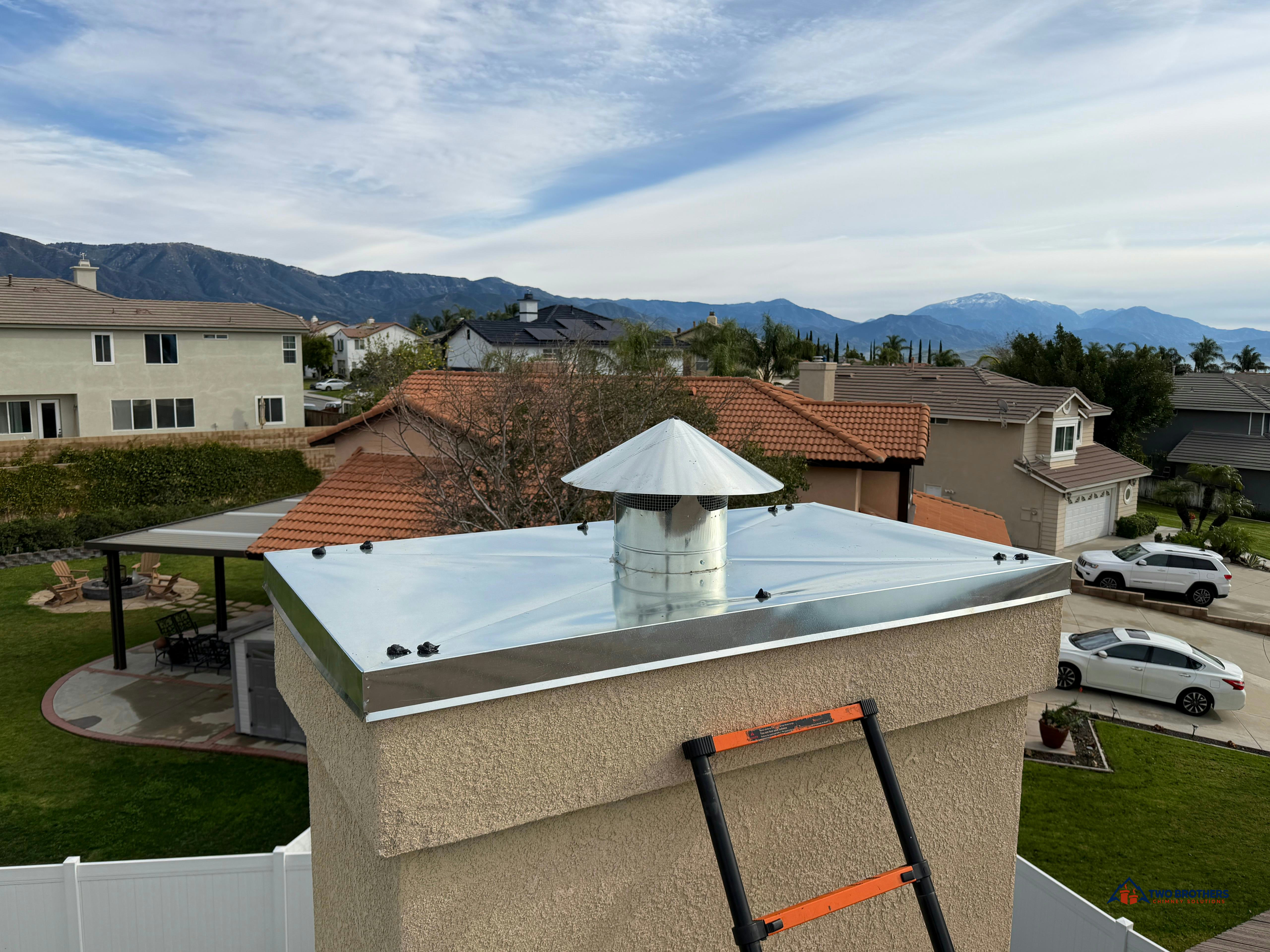 Metal chimney top with a ladder resting against the chimney