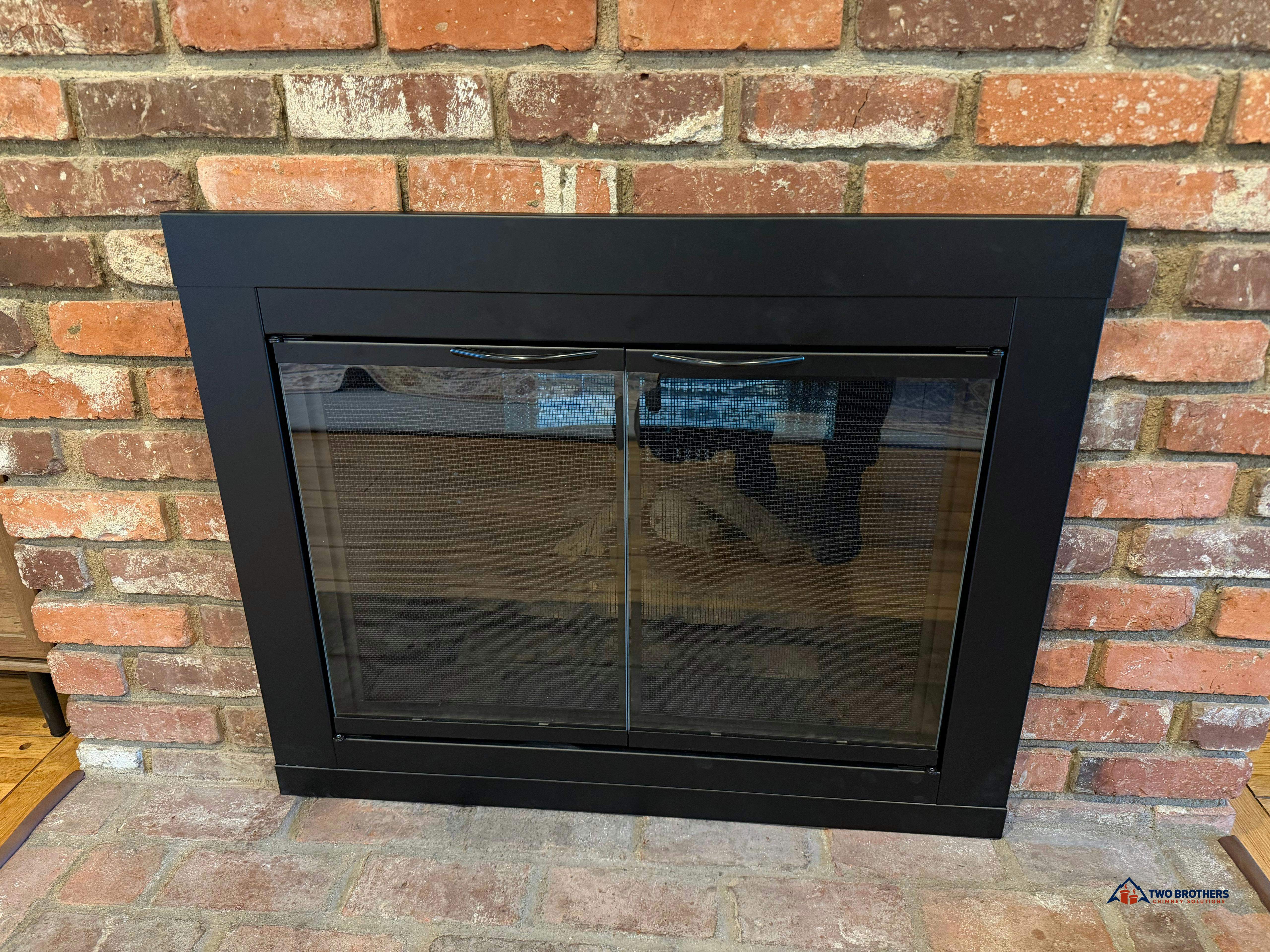 Black glass fireplace doors in a brick surround