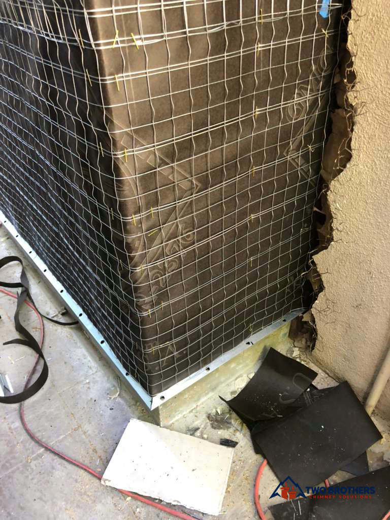 Building paper and wire lath at the base of a fireplace enclosure