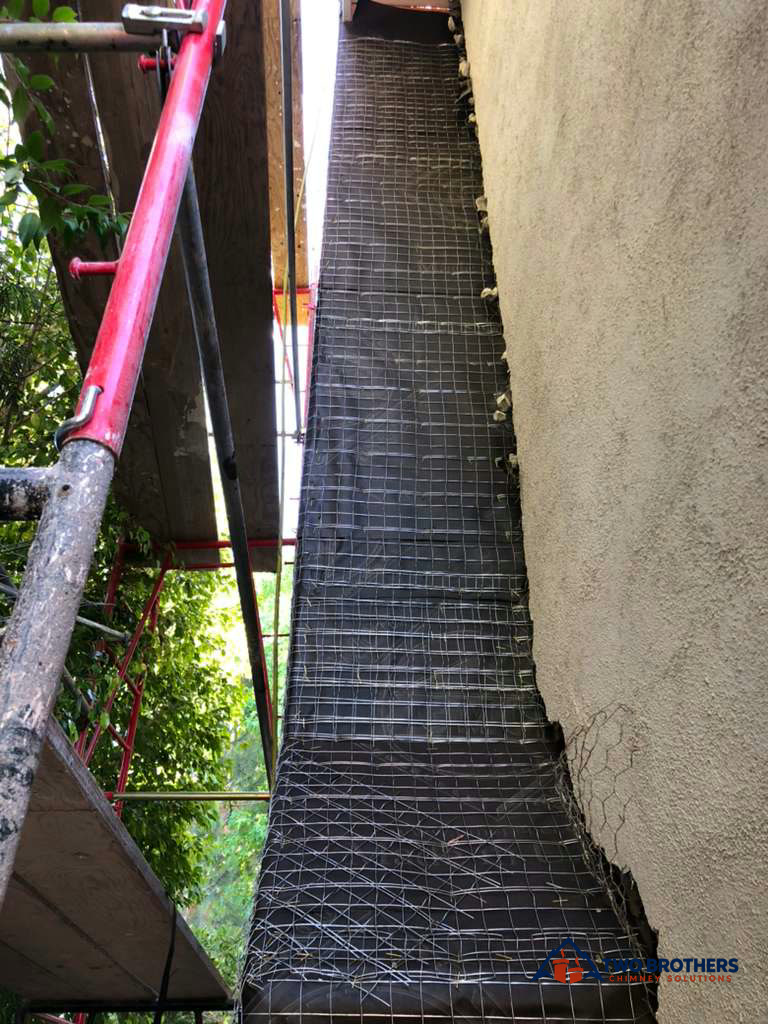 Wire lath on an exterior enclosure alongside scaffolding
